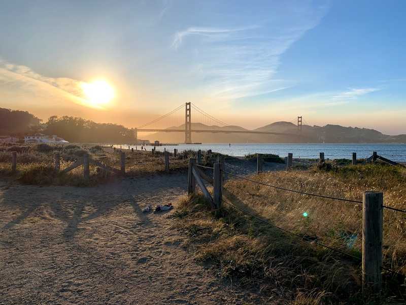 The sun shines above the Golden Gate Bridge, viewed from Crissy Field